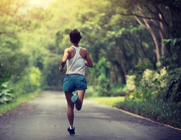 Woman running down a tree-lined path
