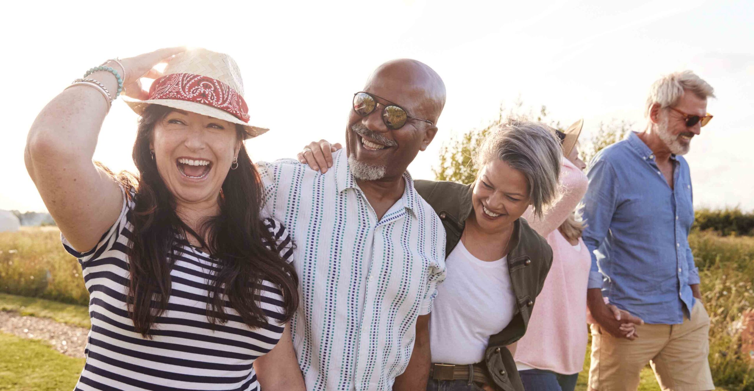 Group of middle-aged to older adults walking outside together, holding hands and smiling